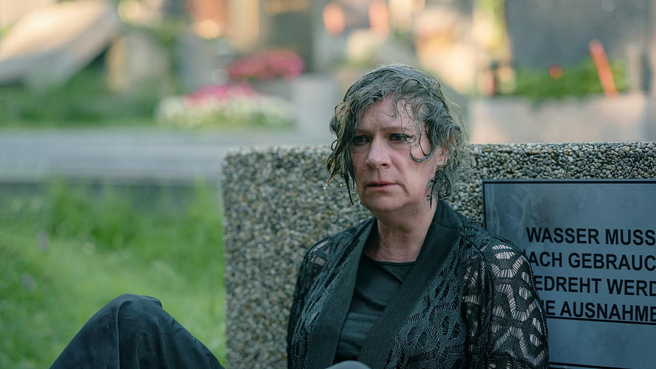 © ORF/Amazon/MGM Eine schwarz gekleidete Frau sitzt am Boden und lehnt an die Wand eines Wasserbehälters, mit nassem Kopf blickt sie erschüttert zum Boden