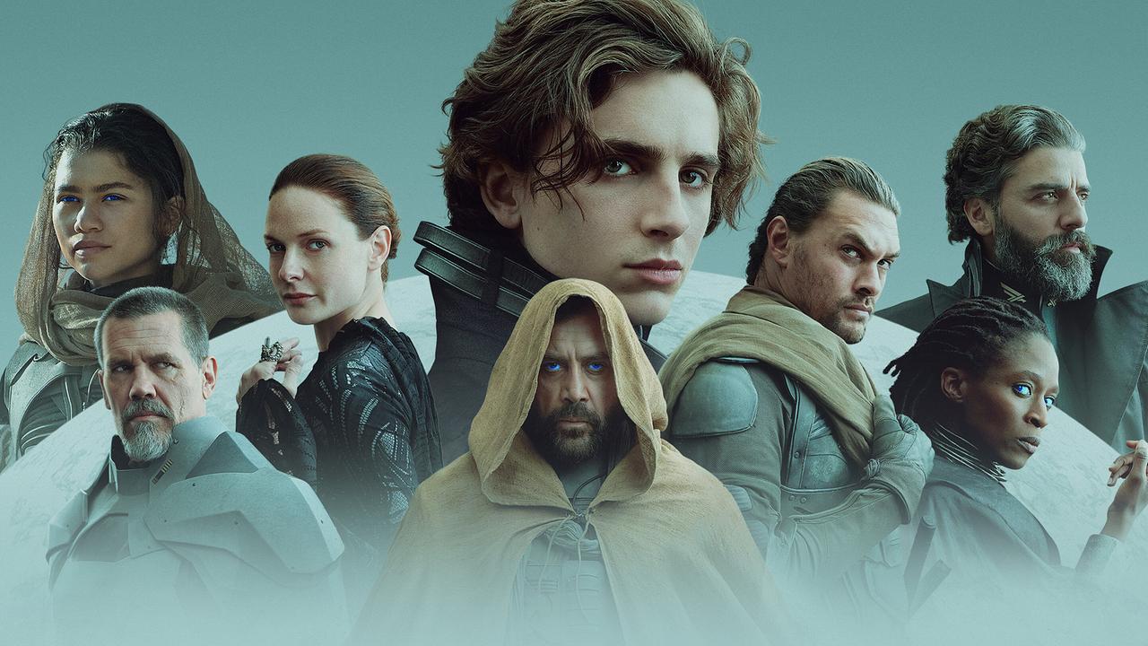 Eine Gruppe von acht Personen in futuristischen Wüstengewändern vor stilisierten Sanddünen