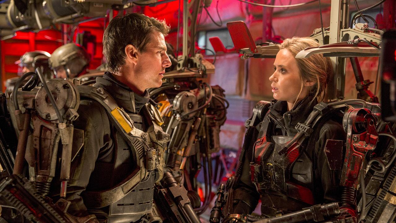 © ORF/Warner Bros. Pictures Tom Cruise als Major Bill Cage und Emily Blunt als Rita Vrataski tragen Exoskelette und stehen sich gegenüber und schauen sich ernst an