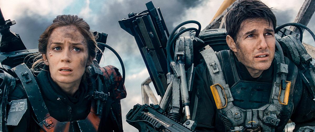 © ORF/Warner Bros. Pictures Emily Blunt als Rita Vrataski und Tom Cruise als Major Bill Cage, in einem Schlachtfeld tragen beide Exoskelette und blicken mit verschmutzten Gesichtern nach vorne