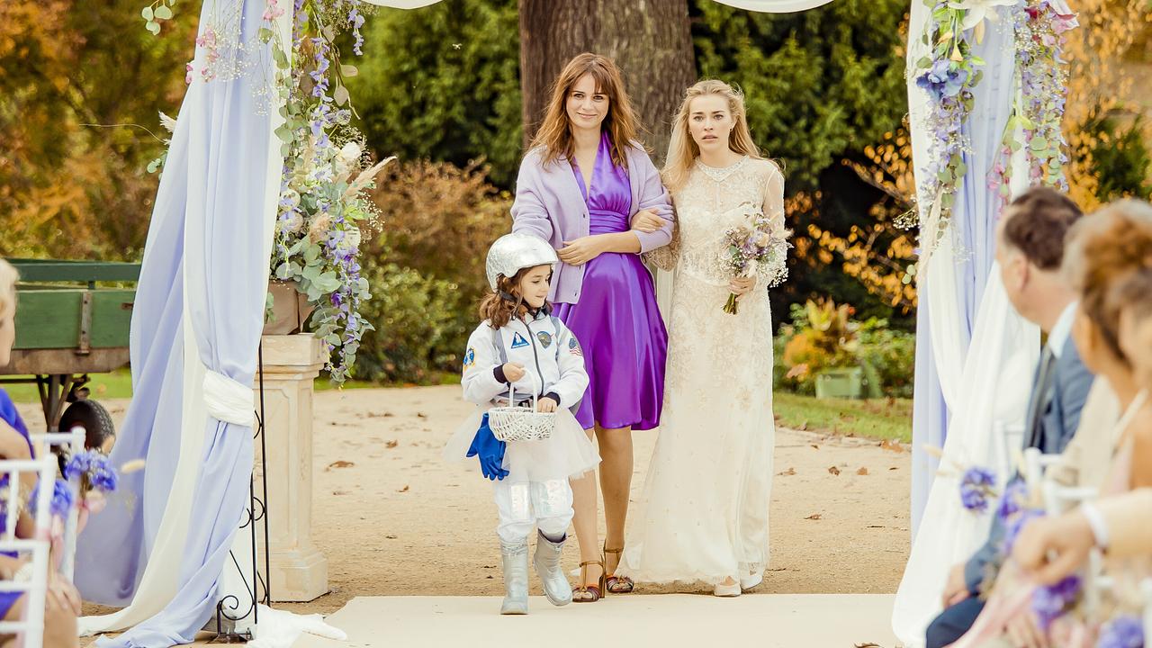 © ORF/ProSieben/Hellinger/Doll Filmproduktion GmbH/Warner Bros. Nora Tschirner als Jule und Milena Tscharntke als deren Schwester Johanna im Hochzeitskleid stehen vor versammelter Hochzeitsgästen erwartungsvoll nebeneinander, vor ihnen ein Mädchen in Astronautinnenanzug