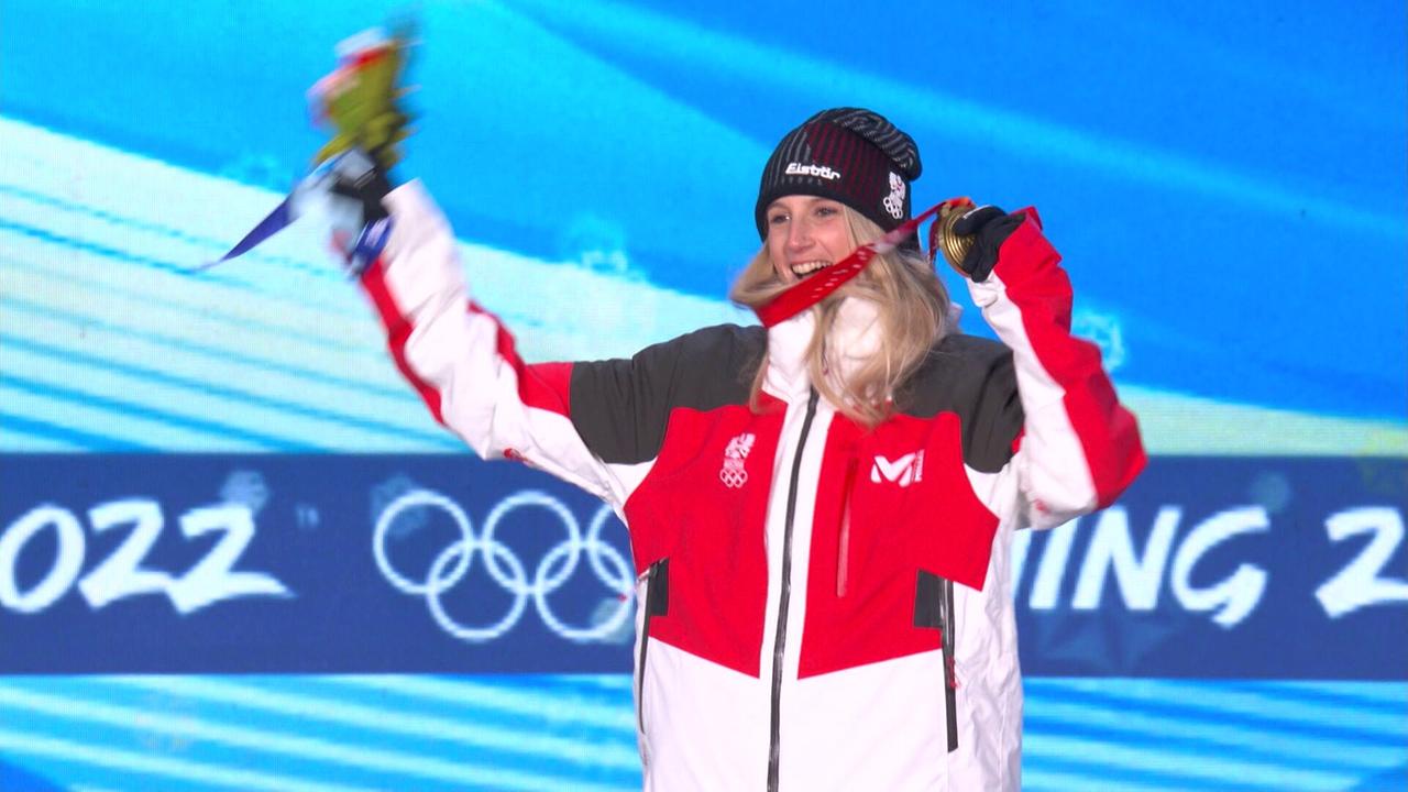© ORF/ORF Sport Anna Gasser feiert ihren Sieg auf einer olympischen Bühne mit Medaille und Blumenstrauß.