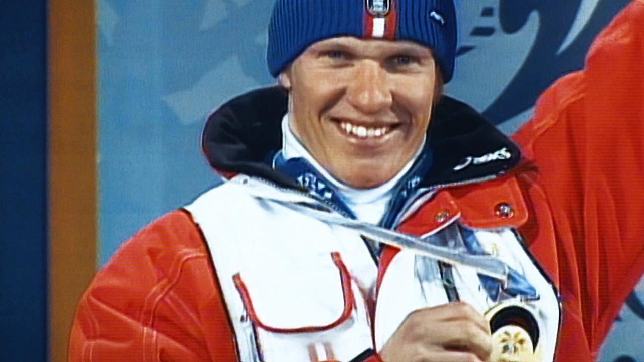 © ORF/ORF Sport Hermann Maier präsentiert stolz eine Medaille auf einer olympischen Bühne.