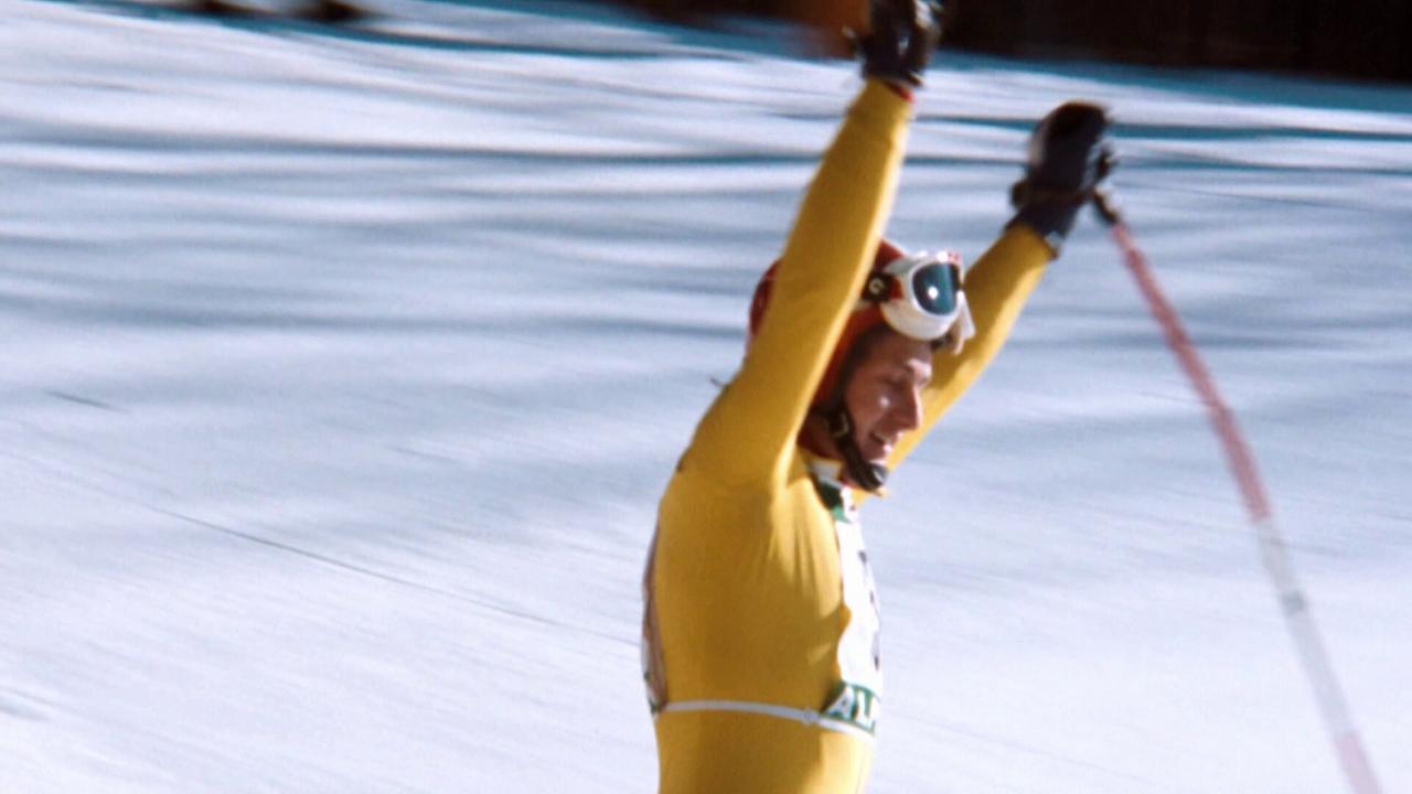 © ORF/ORF Sport Franz Klammer im gelben Skianzug reißt triumphierend die Arme hoch.