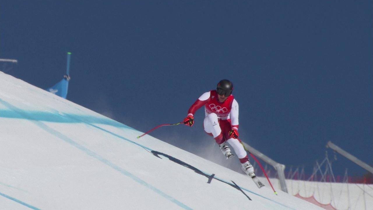 © ORF/ORF Sport Matthias Mayer fährt eine steile Olympia-Piste hinunter und hält dabei beide Stöcke nach hinten.