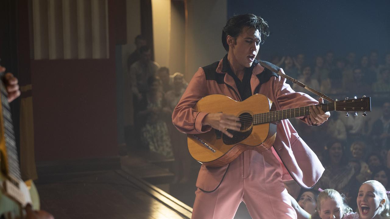 Austin Butler als Elvis Presley im rosaroten Anzug mit Gitarre auf der Bühne bei einem Konzert