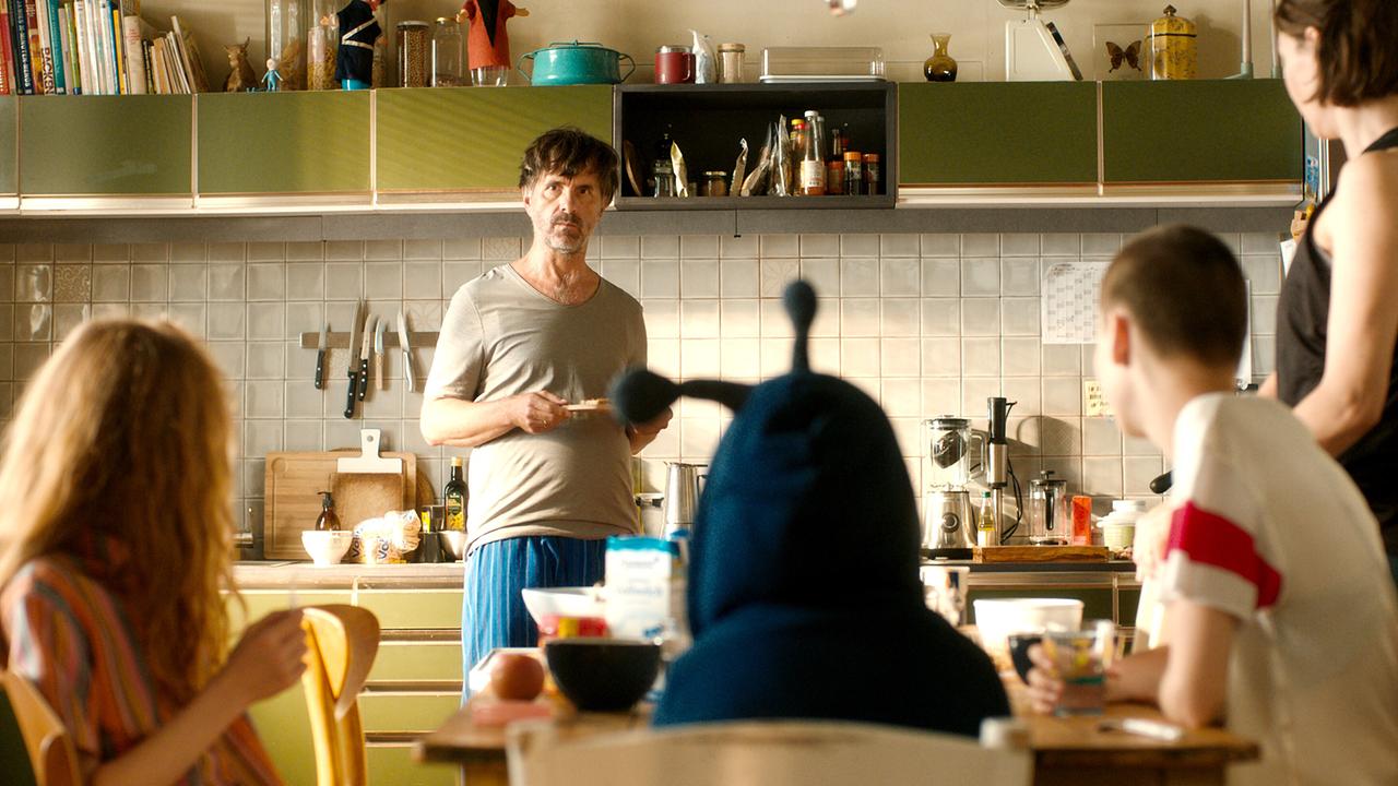 © ORF/Paramount Pictures/Majestic Filmproduktion Christoph Maria Herbst als Paul und Christiane Paul als Emilie mit deren Kindern Mari, Fe und Emilia beim Frühstück, alle schauen auf Paul, der fragend im Pyjama in der Küche steht