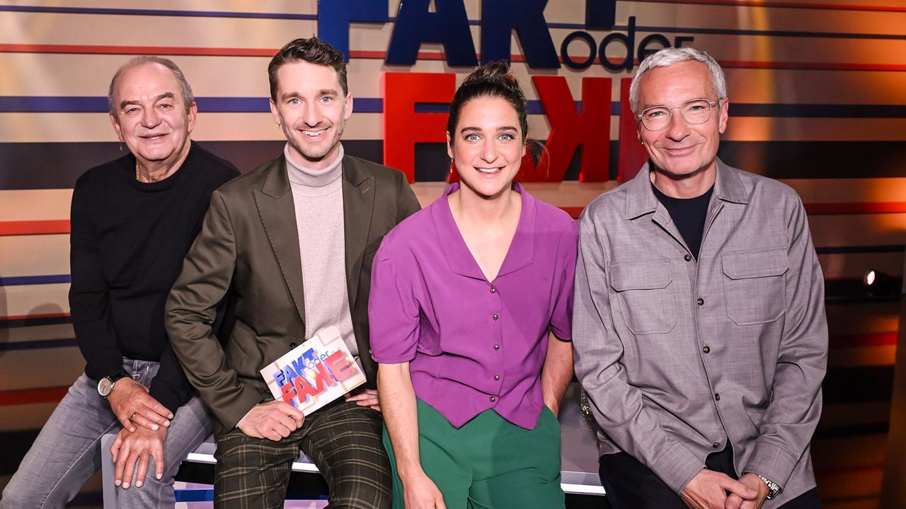 Herbert Prohaska, Clemens Maria Schreiner, Christine Kiesler und Rainer Pariasek sitzen nebeneinander auf dem Moderatorenpult im Fernsehstudio vor dem Schriftzug „FAKT oder FAKE“ 