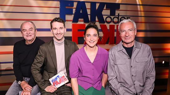 Herbert Prohaska, Clemens Maria Schreiner, Christine Kiesler und Rainer Pariasek sitzen nebeneinander auf dem Moderatorenpult im Fernsehstudio vor dem Schriftzug „FAKT oder FAKE“ 