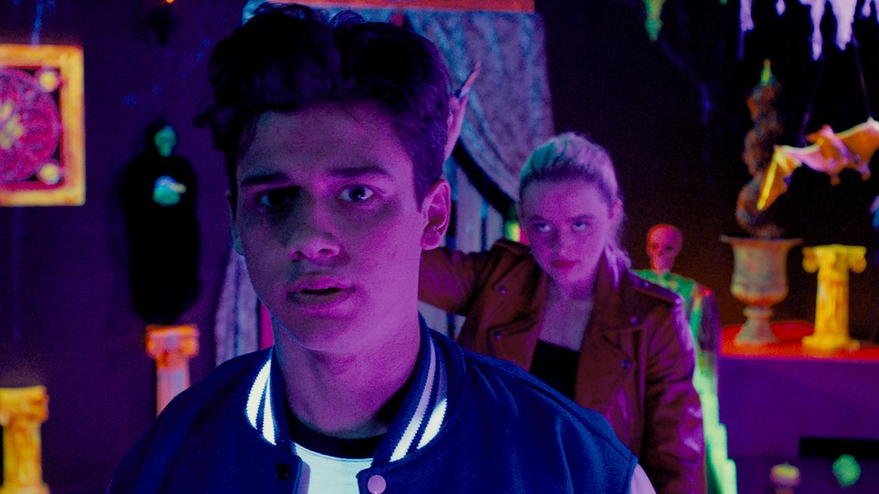 © ORF/Universal Pictures In einem mit Schwarzlicht beleuchteten Raum leuchtet alles neonfarben, Booker Strode schaut vor sich hin, er ahnt nicht, dass Millie sich ihm von hinten nähert