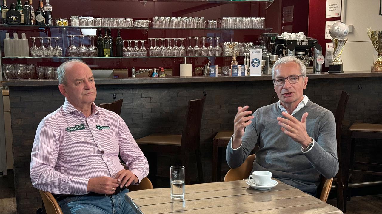 © ORF/DEGN-Film Herbert Prohaska im Gespräch mit Rainer Pariasek, die beiden sitzen an einem Tisch vor einer Theke