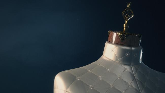 Eine edel ausgeführte Schneiderpuppe, weiße Seide im Karo abgesteppt, kleine Perlen und weiße Stickereien an den Kreuzungspunkten, ein Hals aus fein polierter Holz mit messingfarbenen Beschlägen