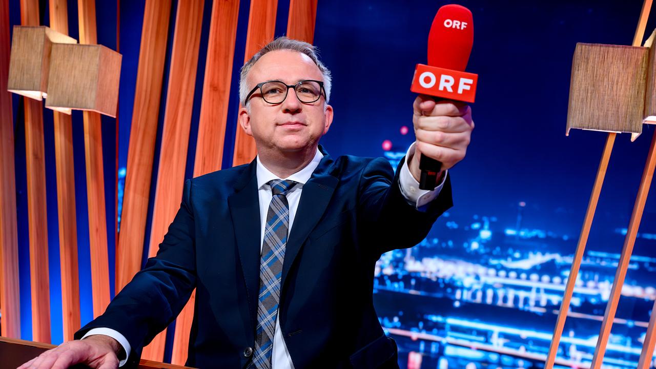 Peter Klien hält ein ORF-Mikro in die Kamera im "Gute Nacht Österreich"-Studio.