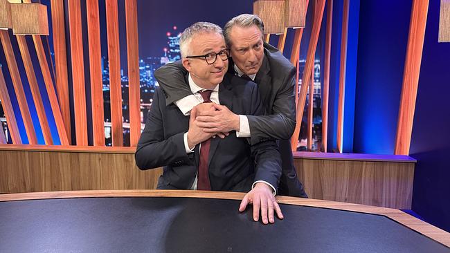 Robert Palfrader umarmt Peter Klien, der am Moderatorenpult sitzt, scherzhaft von hinten im "Gute Nacht Österreich"-Studio