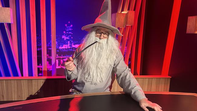 © ORF/Gebhardt Productions Der als Zauberer verkleidete Peter Klien mit langem weißen Bart und spitzem Hut sitzt mit Pfeife am Moderatorenpult im "Gute Nacht Österreich"-Studio