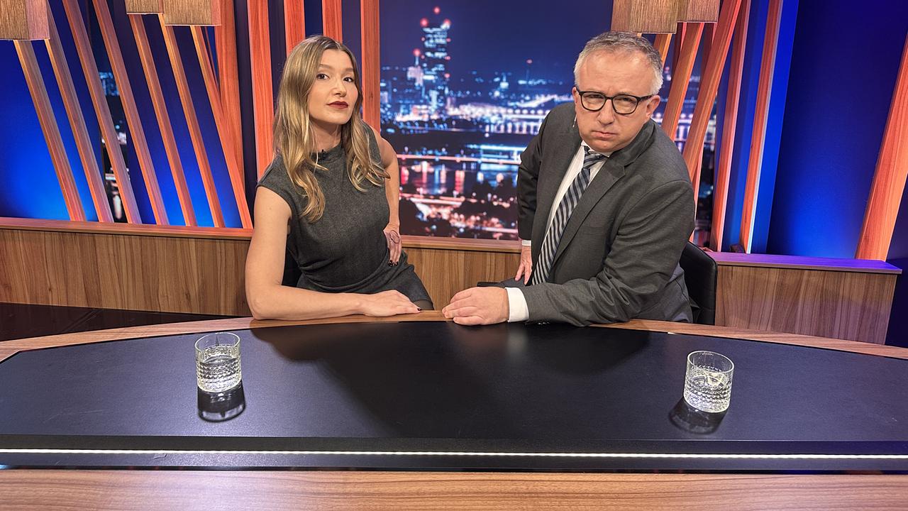Malarina und Peter Klien sitzen am "Gute Nacht Österreich"-Studiotisch vor einer nächtlichen Stadtkulisse. 