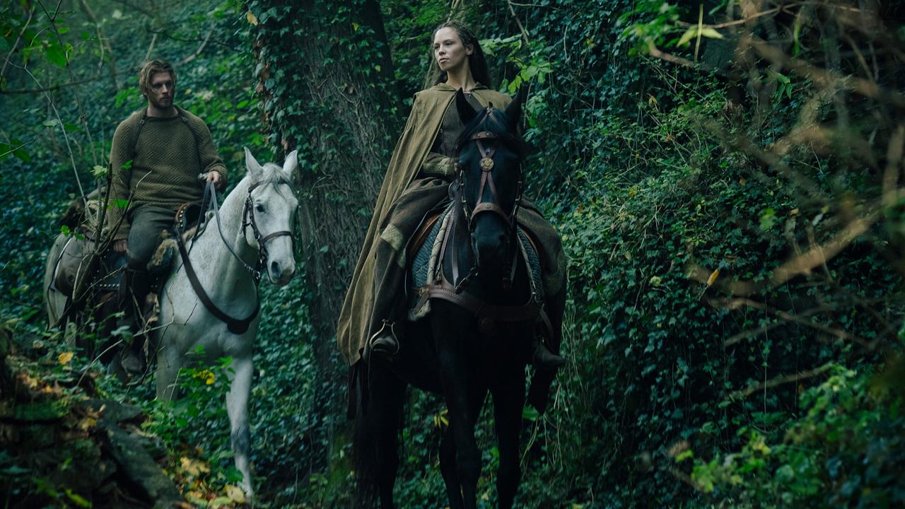 © ORF/Constantin Film Jannis Niewöhner als Siegfried von Xanten und Lilja van der Zwaag als Kriemhild, beide reiten auf ihren Pferden durch einen dichten Wald, beide blicken ernst