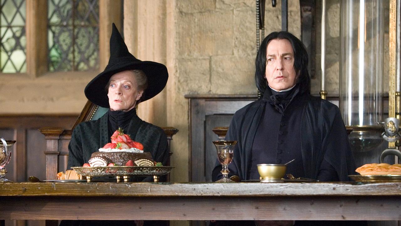 Maggie Smith als Professorin Minerva mit schwarzem hohen Hexenhut und Alan Rickman als Professor Snape in schwarzer Kleidung, die beiden sitzen nebeneinander an einem Tisch des Speisesaals und blicken erstaunt in dieselbe Richtung auf die Reihen der Schülerinnen und Schüler herunter 