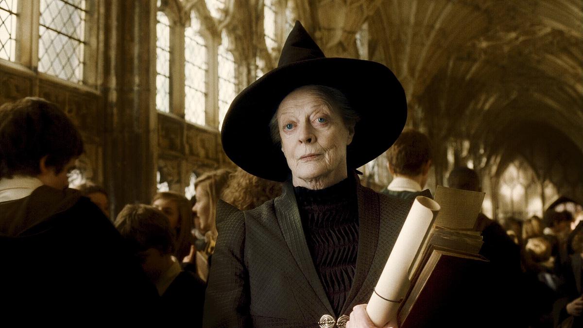 © ORF/Warner Bros. Pictures Maggie Smith als Minerva McGonagall schwarz gekleidet mit Mantel und spitzen Hexenhut, im Getümmel der Schülerinnen und Schüler in der großen Halle steht sie ruhig und blickt besonnen ihr Gegenüber an