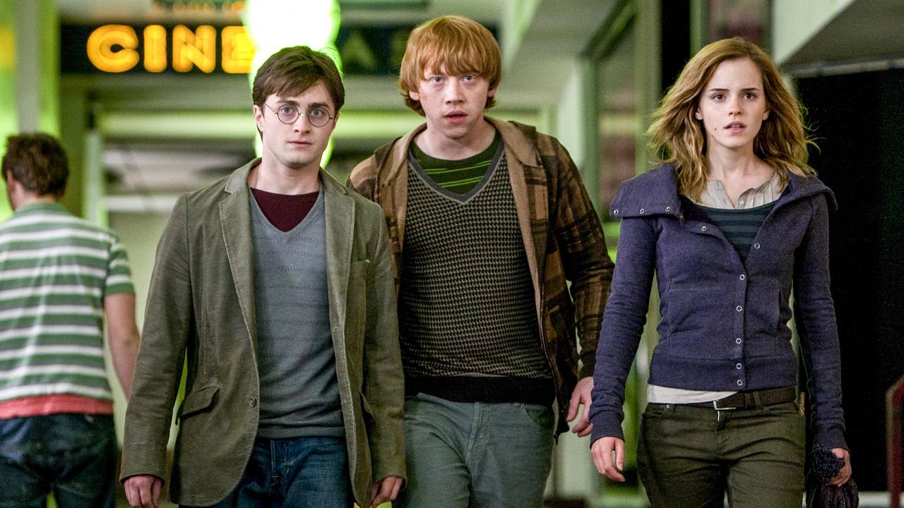 © ORF/Warner Bros. Pictures Harry Potter, Ron Weasley, Emma Watson verlassen gemeinsam ein Kino, im Hintergrund ist die Leuchtschrift CINEMA zu lesen, ernst fokussieren die drei etwas
