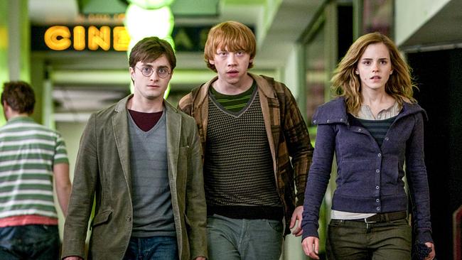 Harry Potter, Ron Weasley, Emma Watson verlassen gemeinsam ein Kino, im Hintergrund ist die Leuchtschrift CINEMA zu lesen, ernst fokussieren die drei etwas