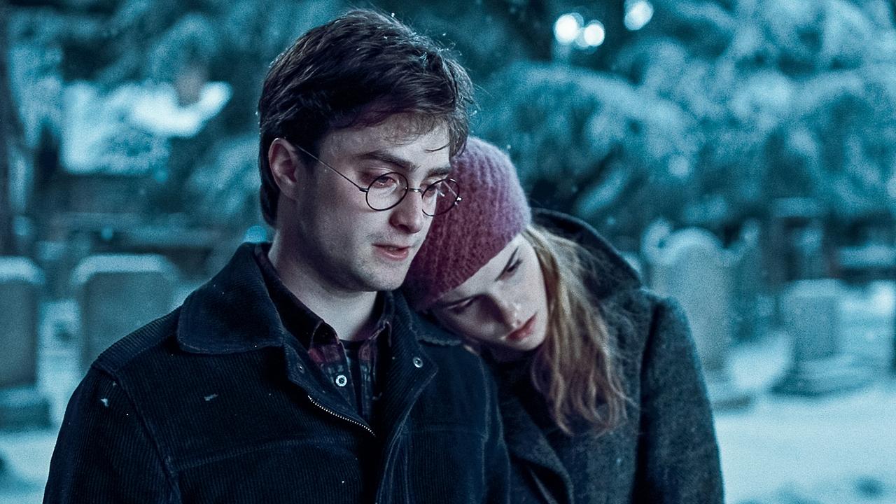 © ORF/Warner Bros. Pictures Daniel Radcliffe als Harry Potter und Emma Watson als Hermine Granger, auf einem verschneiten Friedhof stehen sie nebeneinander vor einem Grab, sie lehnt sich mit ihrem Kopf an seiner Schulter an