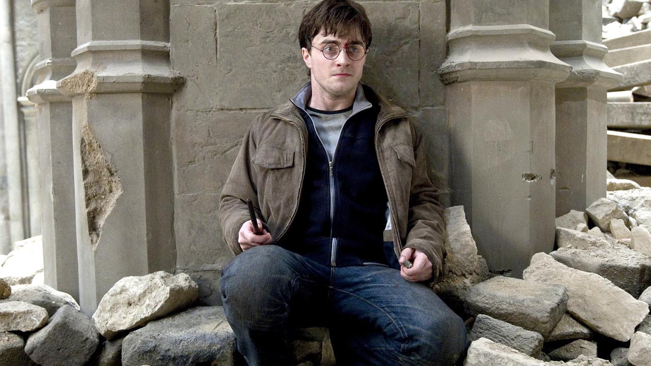 © ORF/TELE-München Daniel Radcliffe sitzt als Harry Potter in einem Stiegenhaus eines alten Gebäudes, die Wände sind beschädigt, Mauersteine liegen überall herum, Harry hält einen Zuaberstab in der Hand und wirkt angespannt