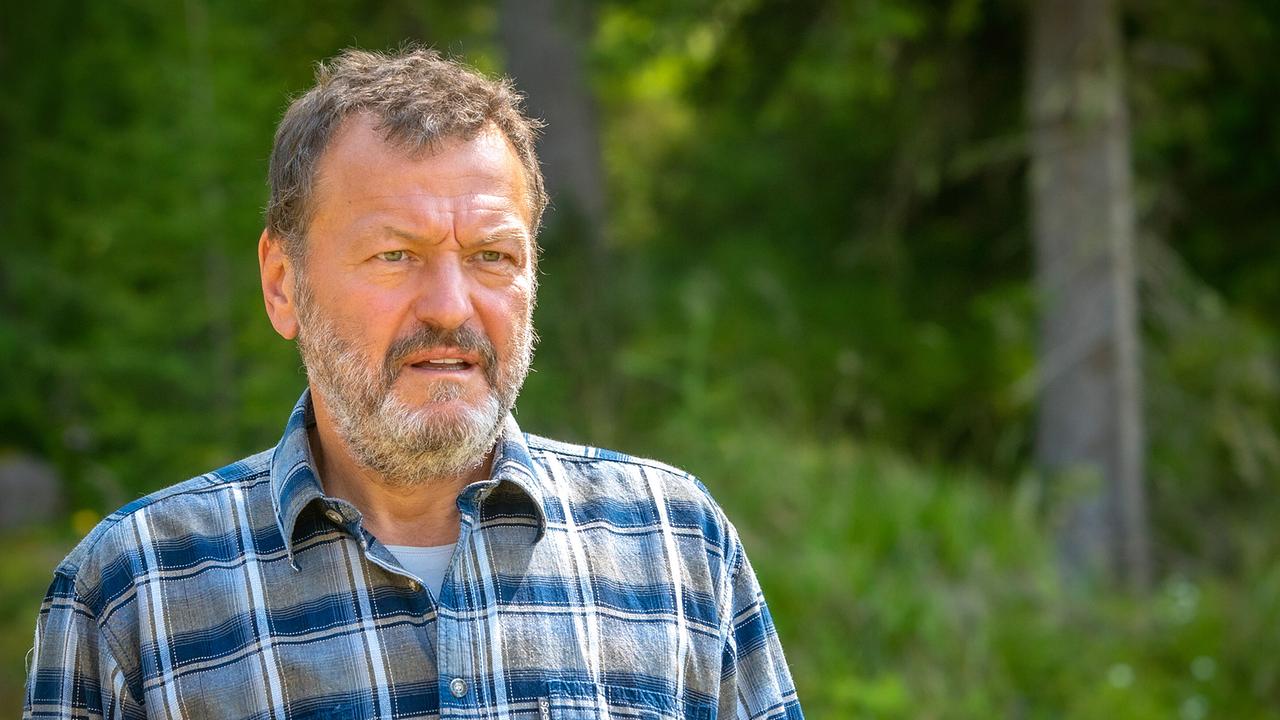 Jakob steht in einem Wald und blickt in die Umgebung.