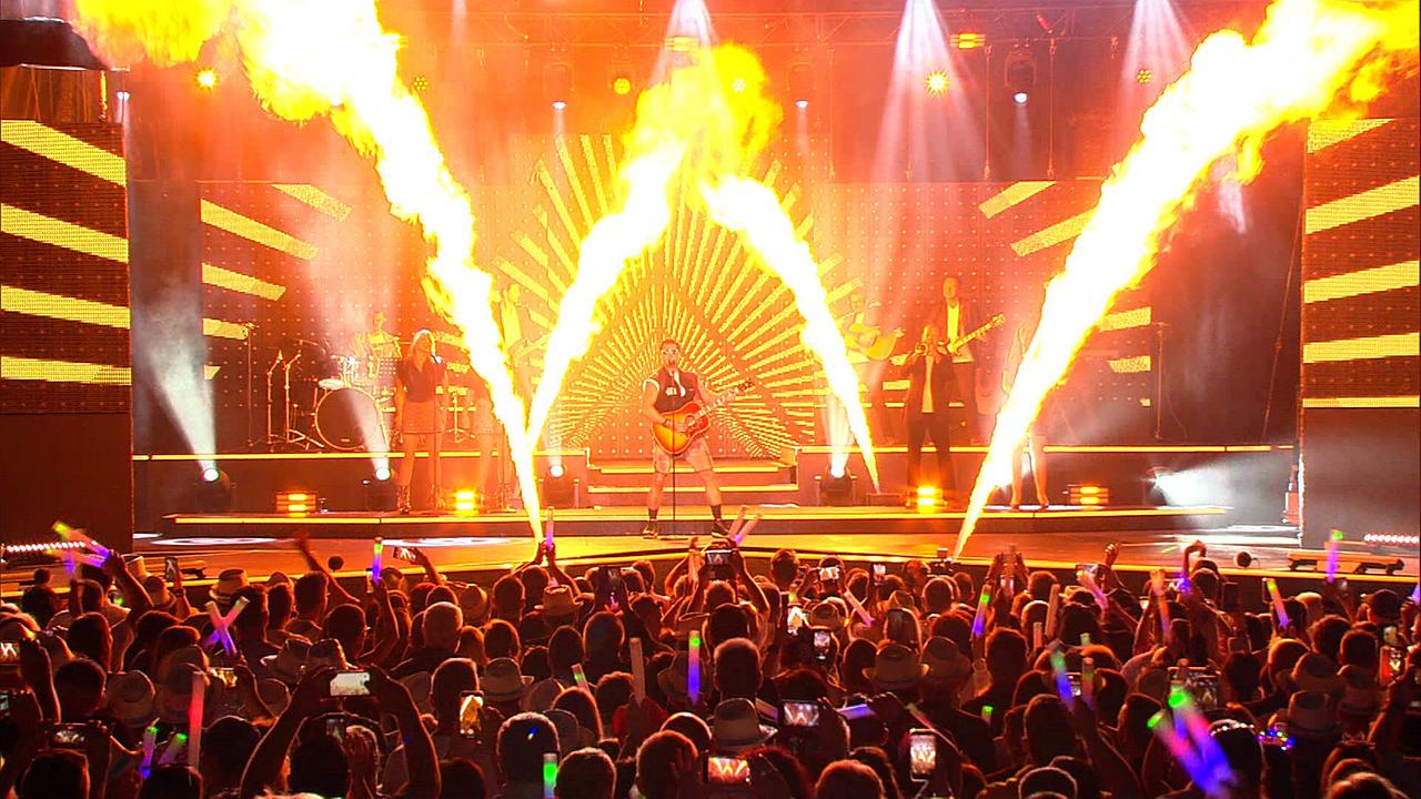 © ORF/Constanze Grießler Andreas Gabalier bei einem Auftritt bei der Starnacht, Feuerfontänen tauchen die Bühne in orangefarbene Farbe