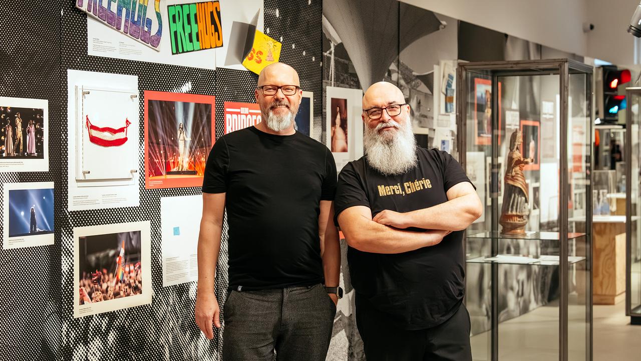 © ORF/Constanze Grießler/Gregor Hofbauer Alkis Vlakassakis und Marco Schreude stehen zwischen den Exponaten ihrer Austellung 'United Queerness'