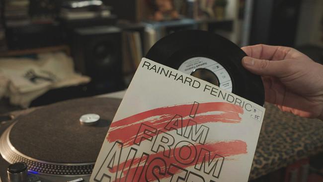 © ORF/LV Eine Hand zieht die Single "I am from Austria" aus dem Schallplattencover, dahinter steht ein Plattenspieler.