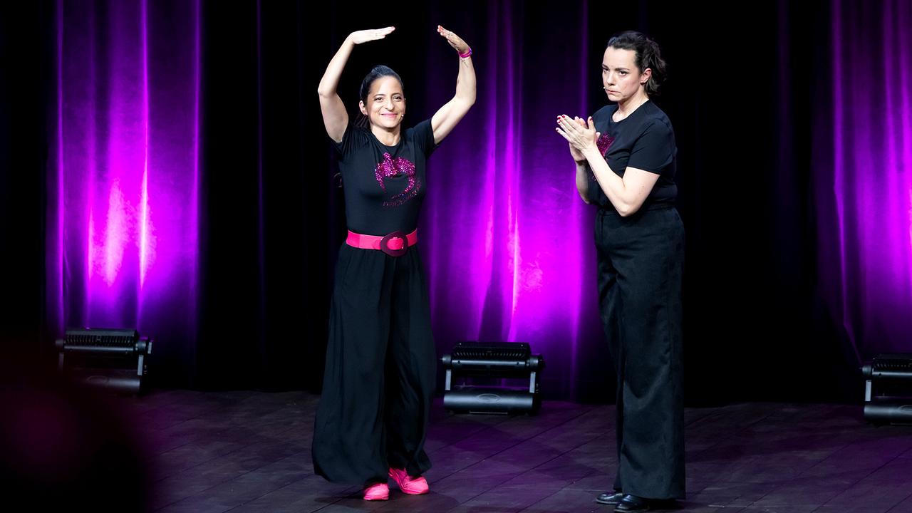 © ORF/Vienna Arts Management/Monika Fellner Caroline Athanasiadis und Gudrun Nikodem-Eichenhardt stehen auf einer Bühne vor violett beleuchteten Vorhänge bei ihrer großen Jubiläumsshow.
