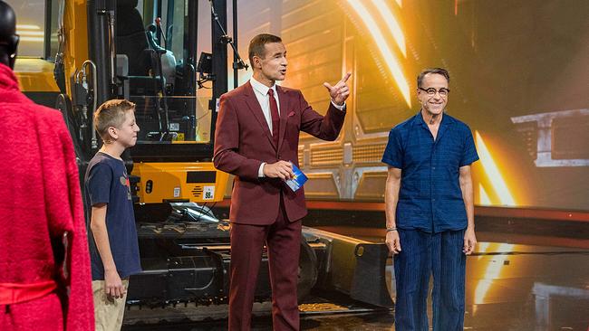 Kai Pflaume mit dem 13-jährigen Joel und Jan Josef Liefers auf einer Bühne vor einem Bagger