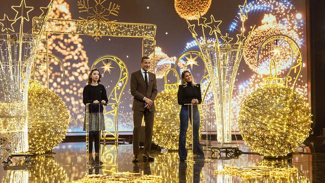 Louise (12), Kai Pflaume und Helene Fischer stehen beim Christmas-Songs-Duell zwischen riesigen, golden leuchtenden Weihnachtsdeko‑Skulpturen, die wie funkelnde Lichtinstallationen den ganzen Raum erstrahlen lassen.