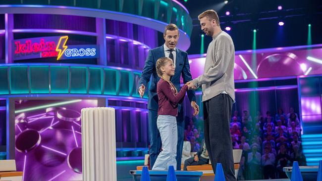 © ORF/NDR/Thorsten Jander Talea (10) steht auf einem Balance-Board und hält die Hand von Christoph Kramer, daneben steht Kai Pflaume im bunten TV-Studio.