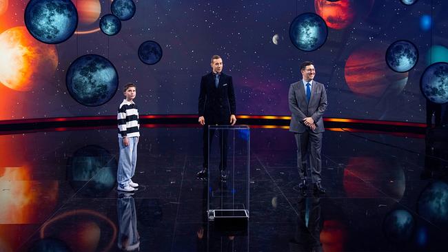 © ORF/NDR/Thorsten Jander Vor einem kosmischen Bühnenhintergrund mit Planeten stehen Frederik, Kai Pflaume und Sebastian Jacoby beim Globus-Duell zusammen.