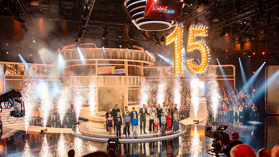 Zum 15-Jahr-Jubiläum der Sendung stehen Kinder, Gäste und Moderator Kai Pflaume zwischen Fontänen und einer großen leuchtenden „15“ auf der Bühne.
