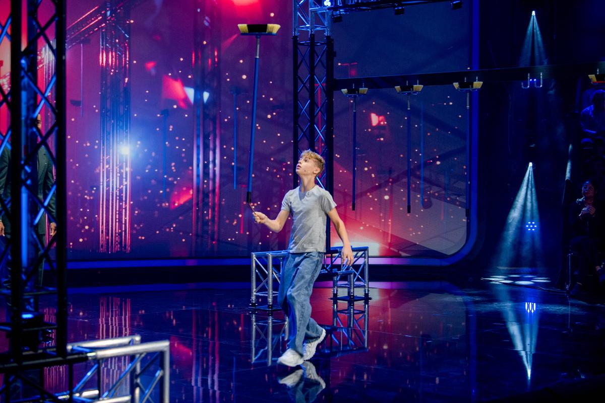 © ORF/NDR/MBTV - Produktions GmbH/Thorsten Jander Brixton (12) balanciert einen Besen in seiner Hand beim Besen-Balance-Duell im Studio.