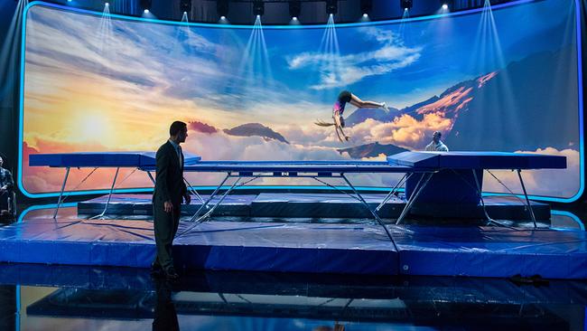 © ORF/NDR/MBTV - Produktions GmbH/Thorsten Jander Sofia (11) zeigt beim Rücken-Salto-Duell zeigt auf einem Trampolin im TV-Studio einen akrobatischen Salto vor einer Bergkulisse auf der Videowand. Kai Pflaume steht daneben.