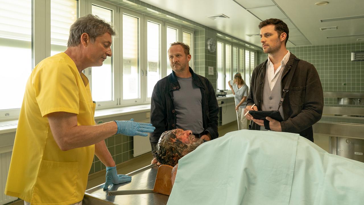 Pathologe Dr. Wippler unterrichtet Max und Felix am Sektionstich die Ergebnisse der Autopsie des Mordopfers