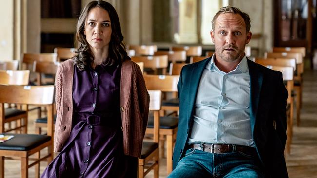 © ORF/SAT1/MR Film/Petro Domenigg Julia und Max Steiner sitzen an Stühlen gefesselt in der ersten Reihe eines leeren Zuschauerraums und blicken ernst Richtung Bühne