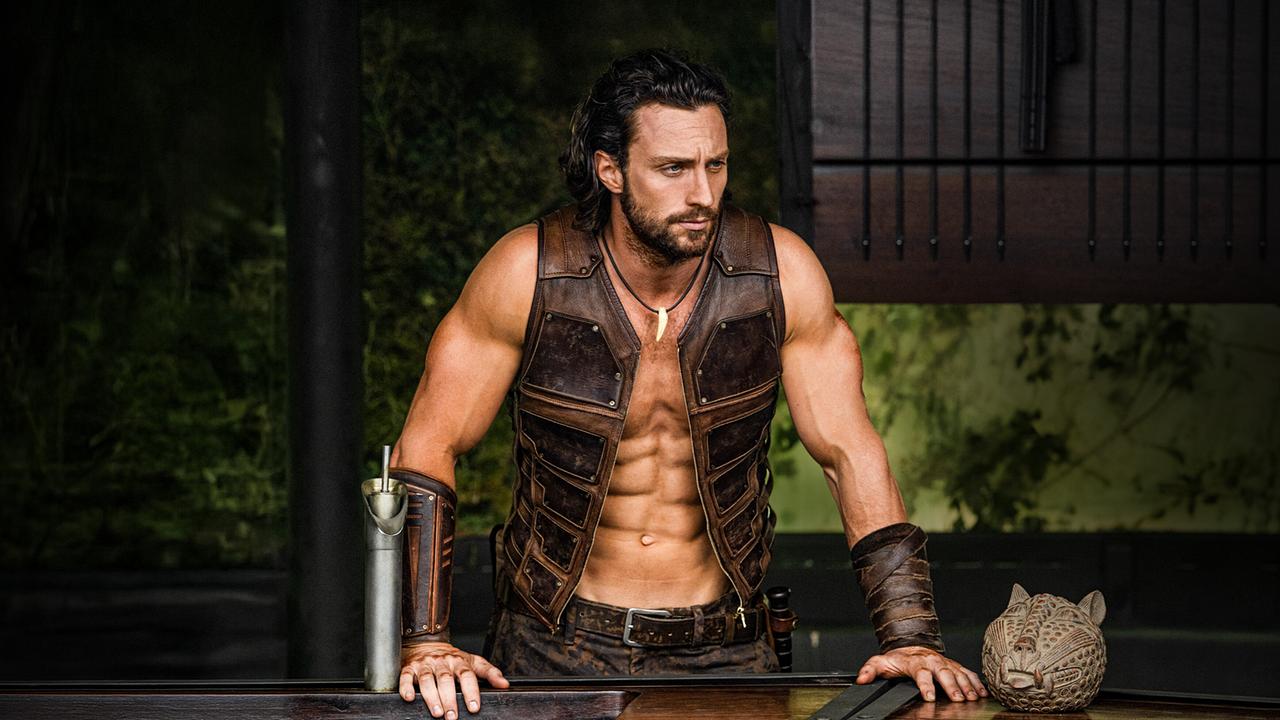 Aaron Taylor-Johnson als Sergei Kravinoff beziehungsweise Kraven - in offener ärmelloser Lederjacke stüzt er sich an ein Geländer und blickt nach unten