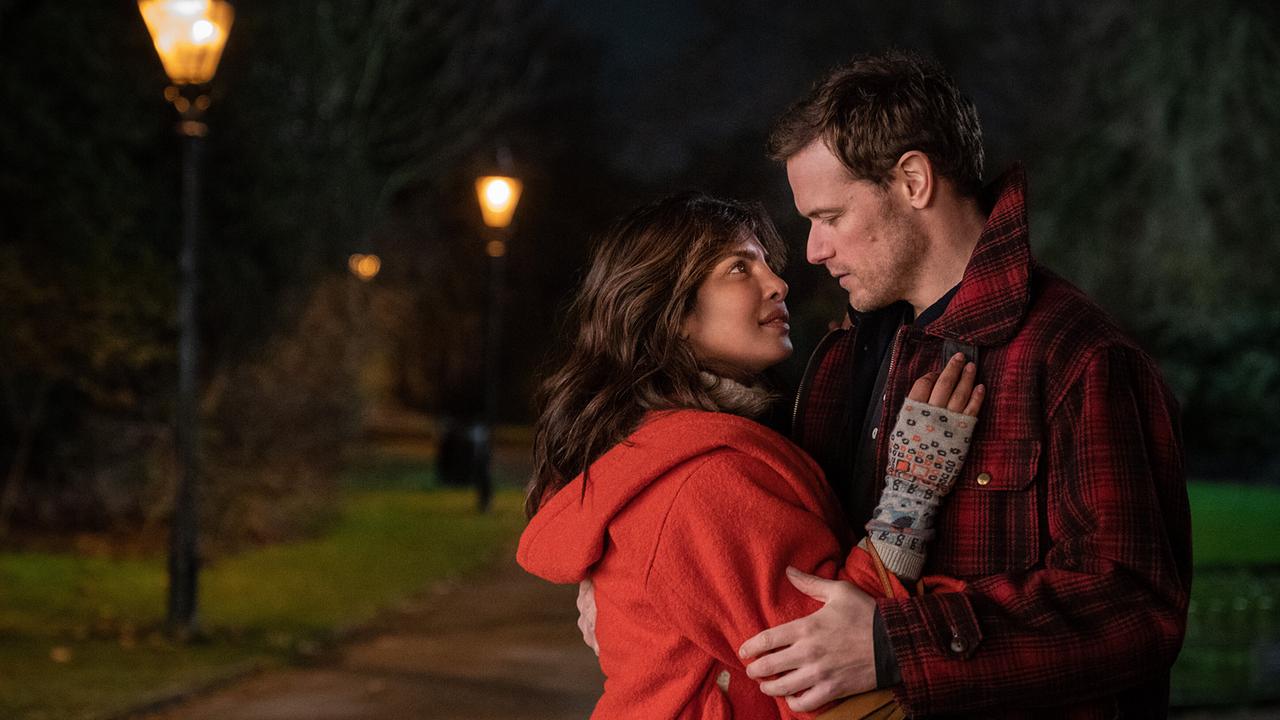 In einem Park in der Nacht liegen sich eine Frau und ein Mann in den Armen und blicken sich tief in die Augen