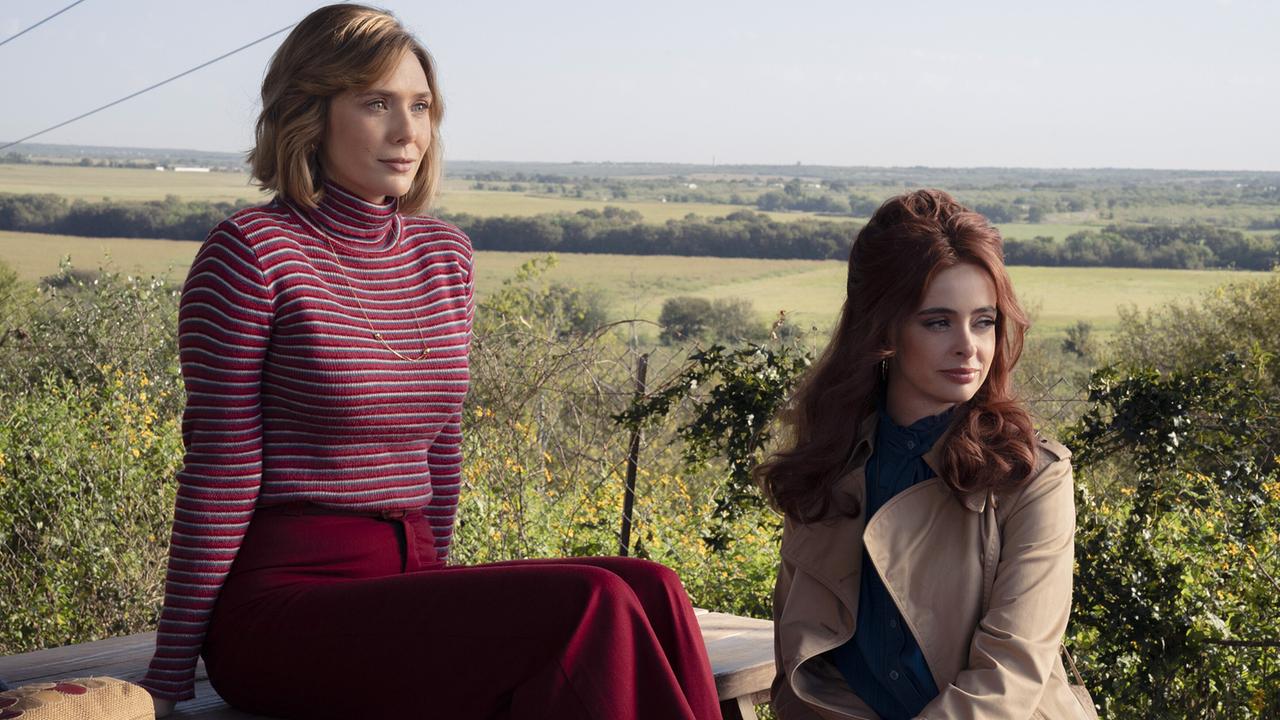 © ORF/Warner/HBO Max Elizabeth Olsen als Candy Montgomery und Krysten Ritter als Sherry Cleckle, die beiden Freundinnen machen auf einem Hügel auf einer Bank im Freien eine Rast, beide blicken freundlich lächelnd in dieselbe Richtung, hinter ihnen der Blick in die Ebene, Äcker, Wiesen und Wälder sind zu sehen