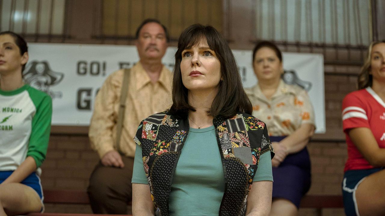 © ORF/Warner/HBO Max Lily Rabe sitzt als Betty Gore als Zuschauerin auf der Tribüne einer Sporthalle und folgt dem Volleyballspiel