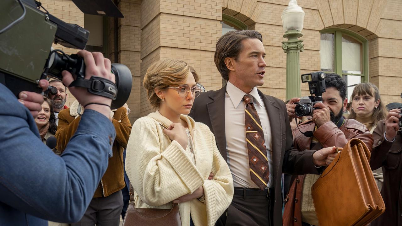 © ORF/Warner/HBO Max Candy Montgomery in weißer Strickjacke und Tom Pelphrey in braunem Anzug mit Krawatte vor dem Justizgebäude, sie schaut ernst vor sich auf den Boden, Kameras und Fotoapparate der Reporter sind auf sie gerichtet