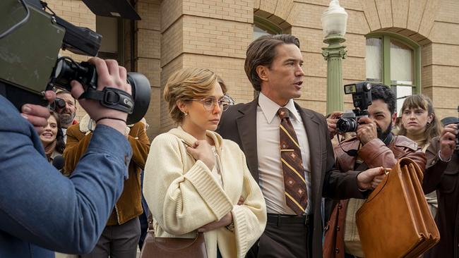 © ORF/Warner/HBO Max Candy Montgomery in weißer Strickjacke und Tom Pelphrey in braunem Anzug mit Krawatte vor dem Justizgebäude, sie schaut ernst vor sich auf den Boden, Kameras und Fotoapparate der Reporter sind auf sie gerichtet