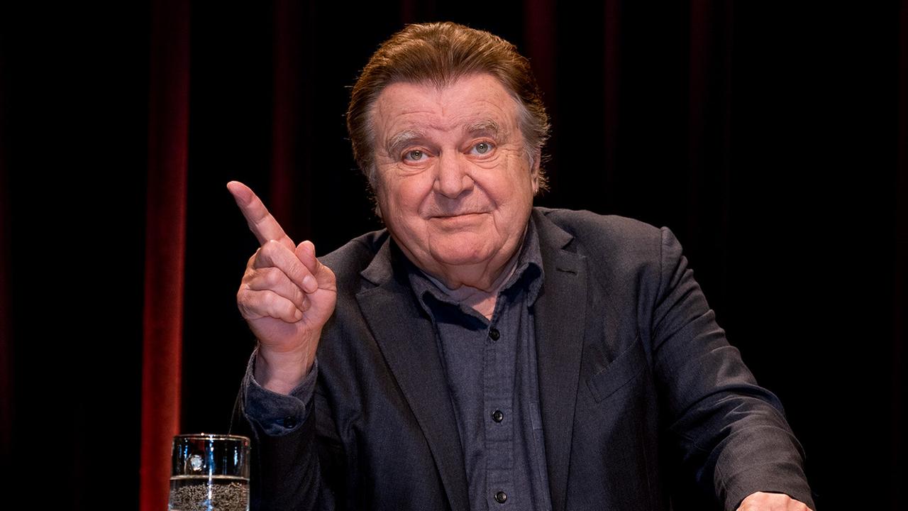 © ORF/E&A/Hans Eder Lukas Resetarits steht hinter einem Pult auf der Bühne und hebt mahnend den Zeigefinger.