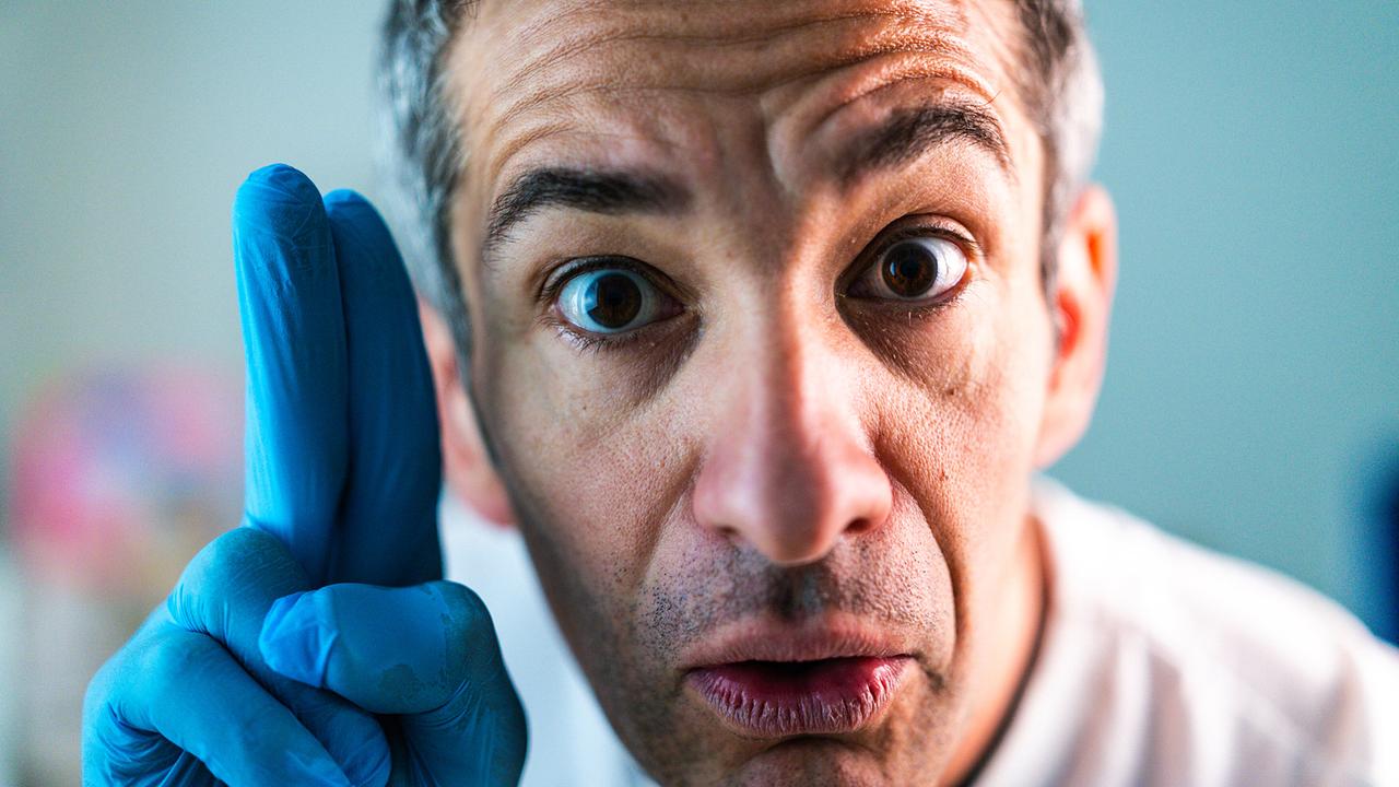 © ORF/Mutterschifffilm/Omar Sarsam Nahaufnahme von Omar Sarsam, der mit blauen Einweghandschuhen in die Kamera zeigt