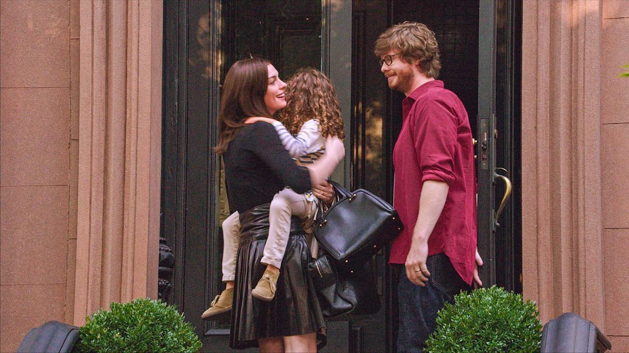 © ORF/Warner Bros. Pictures Anne Hathaway als Jules Ostin und Anders Holm als Matt sprechen freundlich miteinander vor dem Eingangs eines Gebäudes, sie hält ein Mädchen im Arm